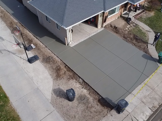 Aerial view of a concrete driveway and wraparound walkway at a home
