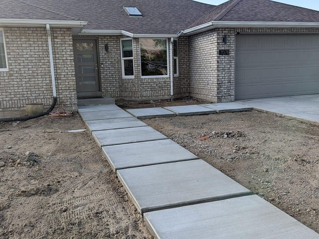 Concrete walkway leading to the front door of a brick home