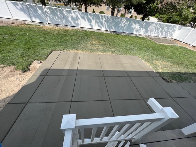Concrete patio with poured steps and a white handrail