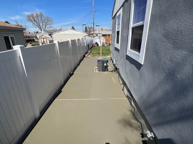 Narrow concrete walkway poured along the side of a house