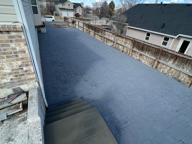 Dark stamped concrete patio with a poured step