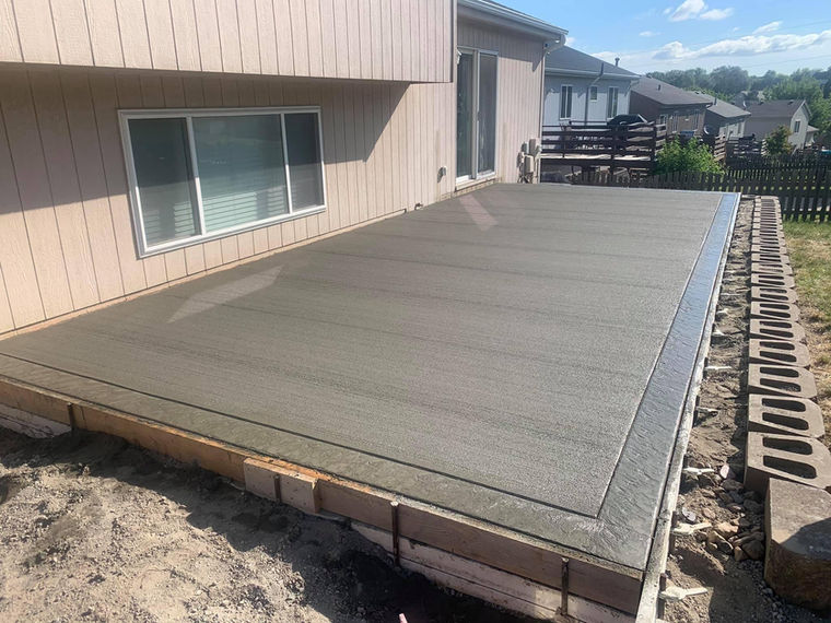 Concrete slab running beside a house next to a block retaining wall